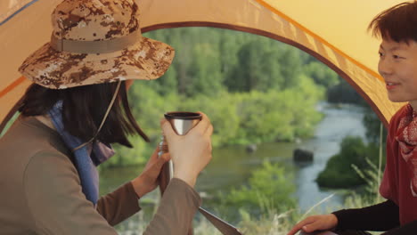 asian tourists using laptop and drinking tea at campsite