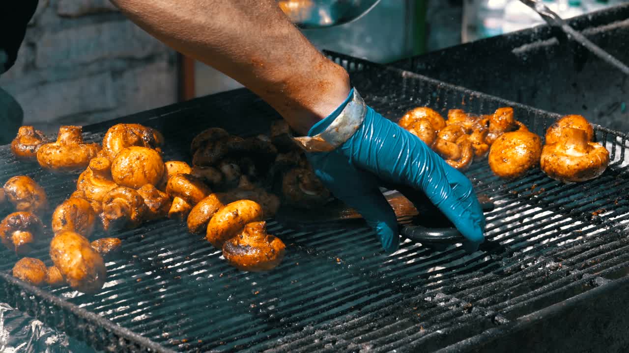 요리사는 그릴에 버섯을 준비합니다. 바베큐 파티