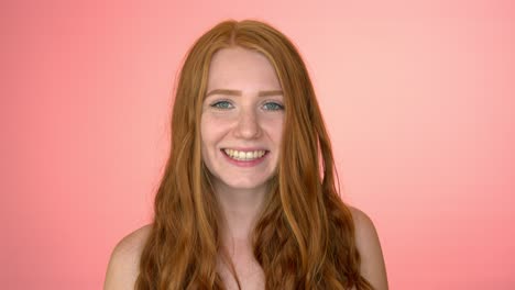 retrato de una hermosa joven mujer de ojos verdes felizmente sonriente, aislada en un fondo de color melocotón