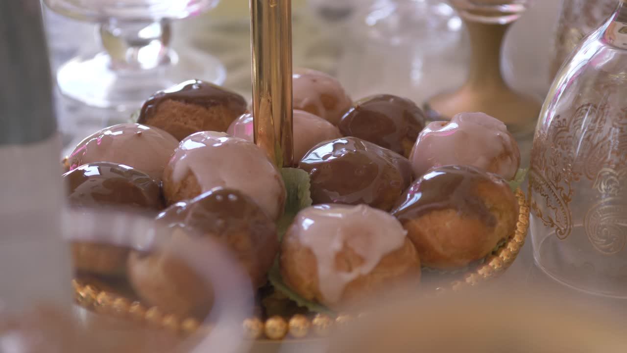 apetitosos choux glaseados exhibidos en una mesa de bodas en un puesto de pasteles de 2 niveles