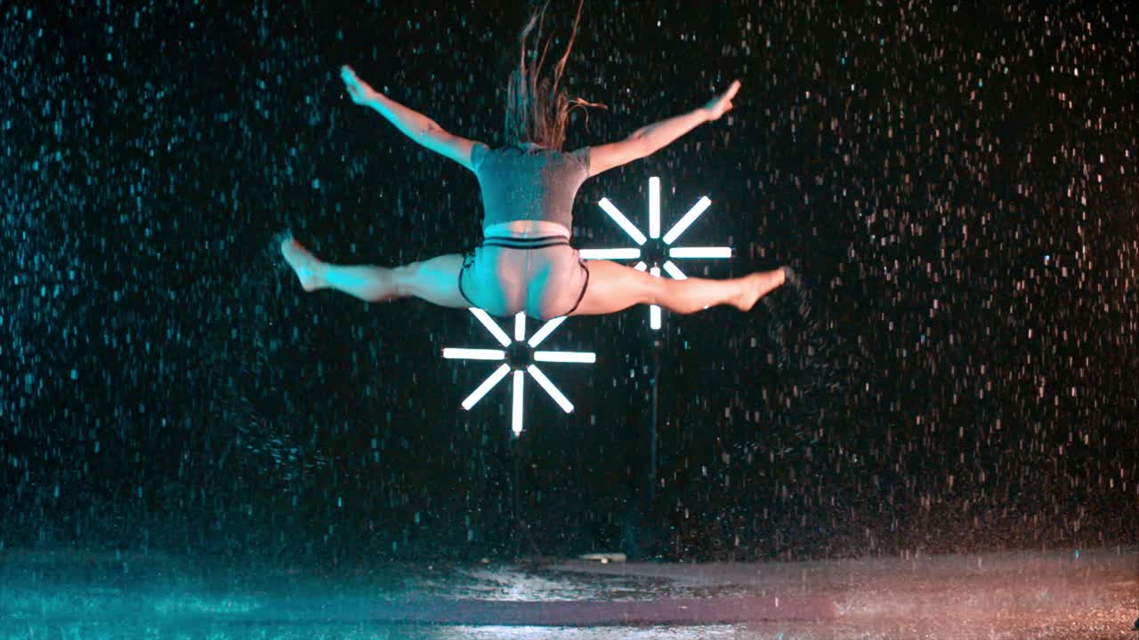 Slow motion jump splits in the rain by performing modern dancer