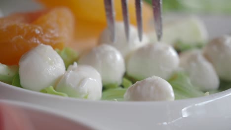 close-up of a fresh caprese salad with mozzarella, orange slices and green leaves