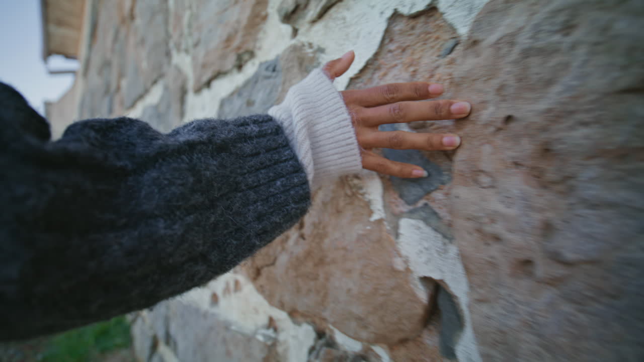 Primo piano di mano di donna che tocca un muro passeggiando nel castello. Donna che percepisce la consistenza della pietra.