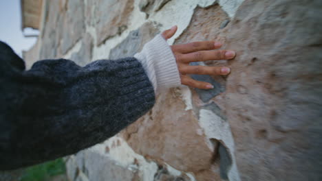 woman hand touching wall strolling castle closeup. lady feeling stoned texture