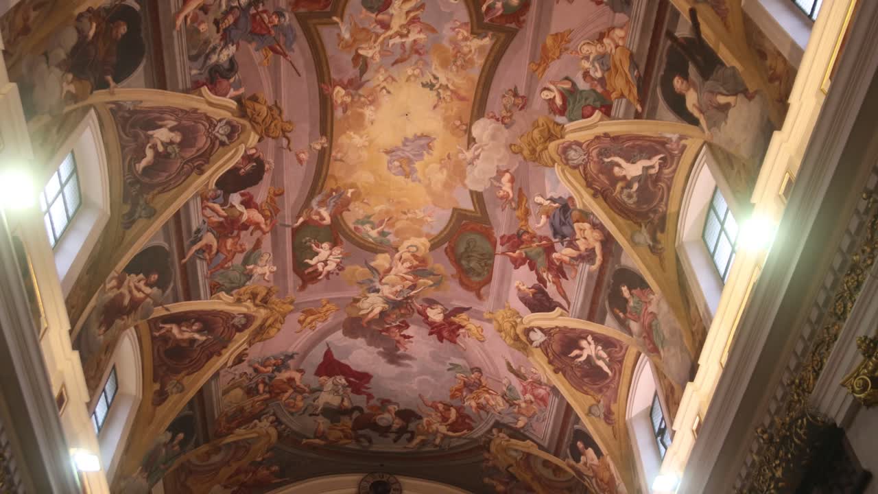 Colorful ceiling fresco in a church featuring detailed religious scenes and ornate decorations.