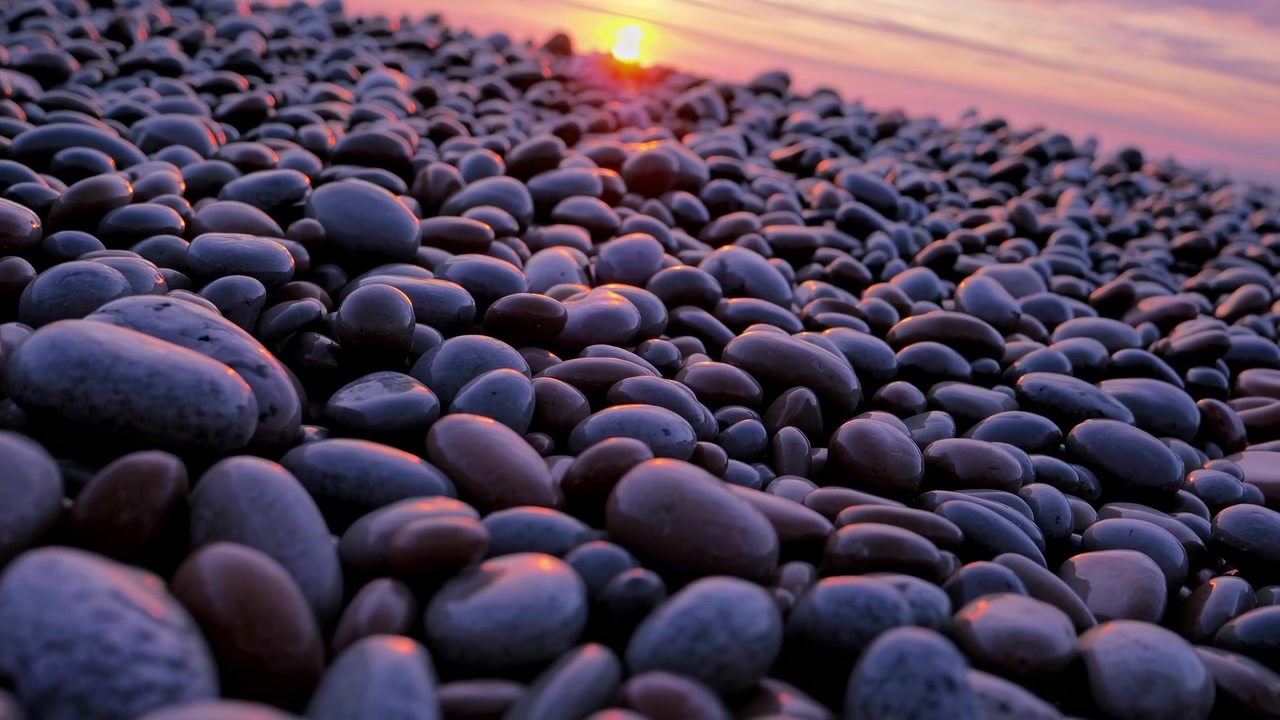 Ciottoli lisci su una spiaggia al tramonto