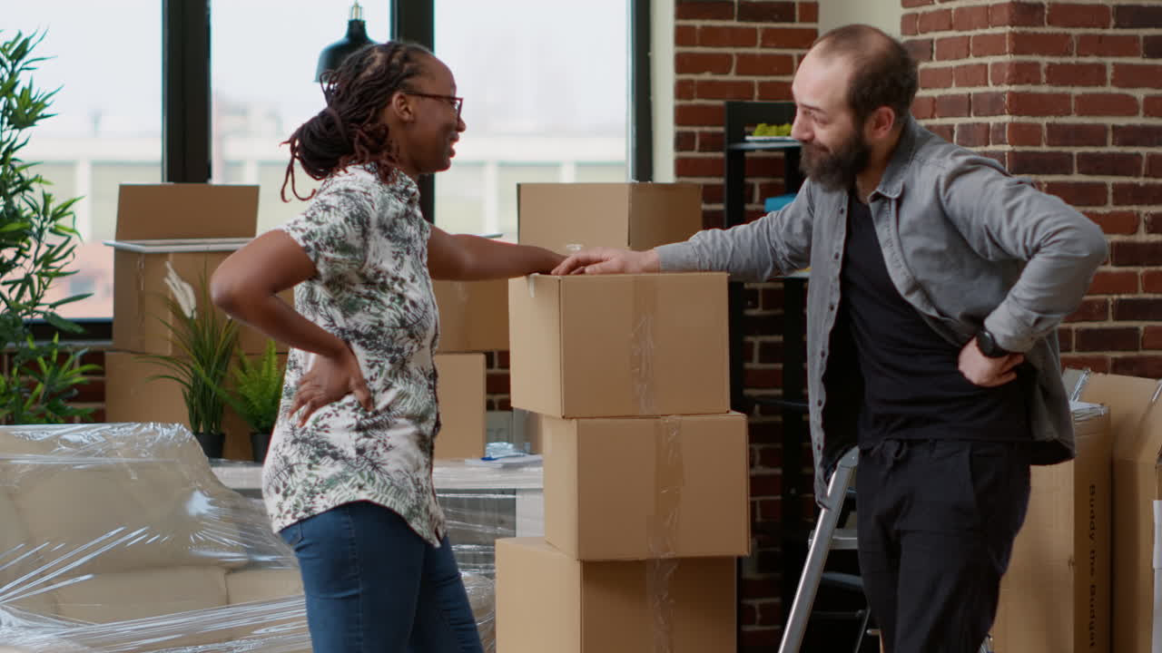 Diverse couple moving in together with carton boxes
