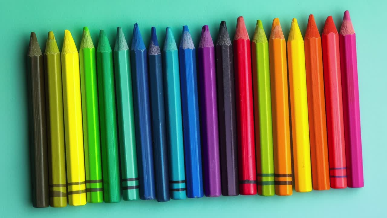 lápices de colores vibrantes alineados contra un fondo turquesa