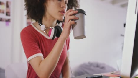 mixed race woman drinking coffee in creative office