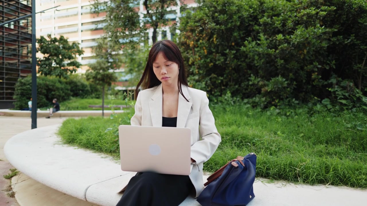 亞洲年輕女子於城市公園戶外使用手提電腦工作