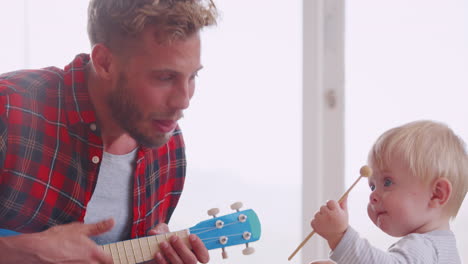 dad and toddler son play with instruments at home, close up