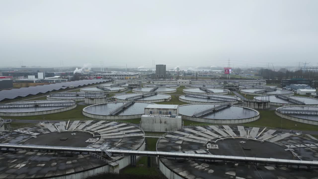 Drone aerial of large wastewater treatment facility at Harnaschpolder featuring multiple circular filtration tanks and Dutch water management infrastructure