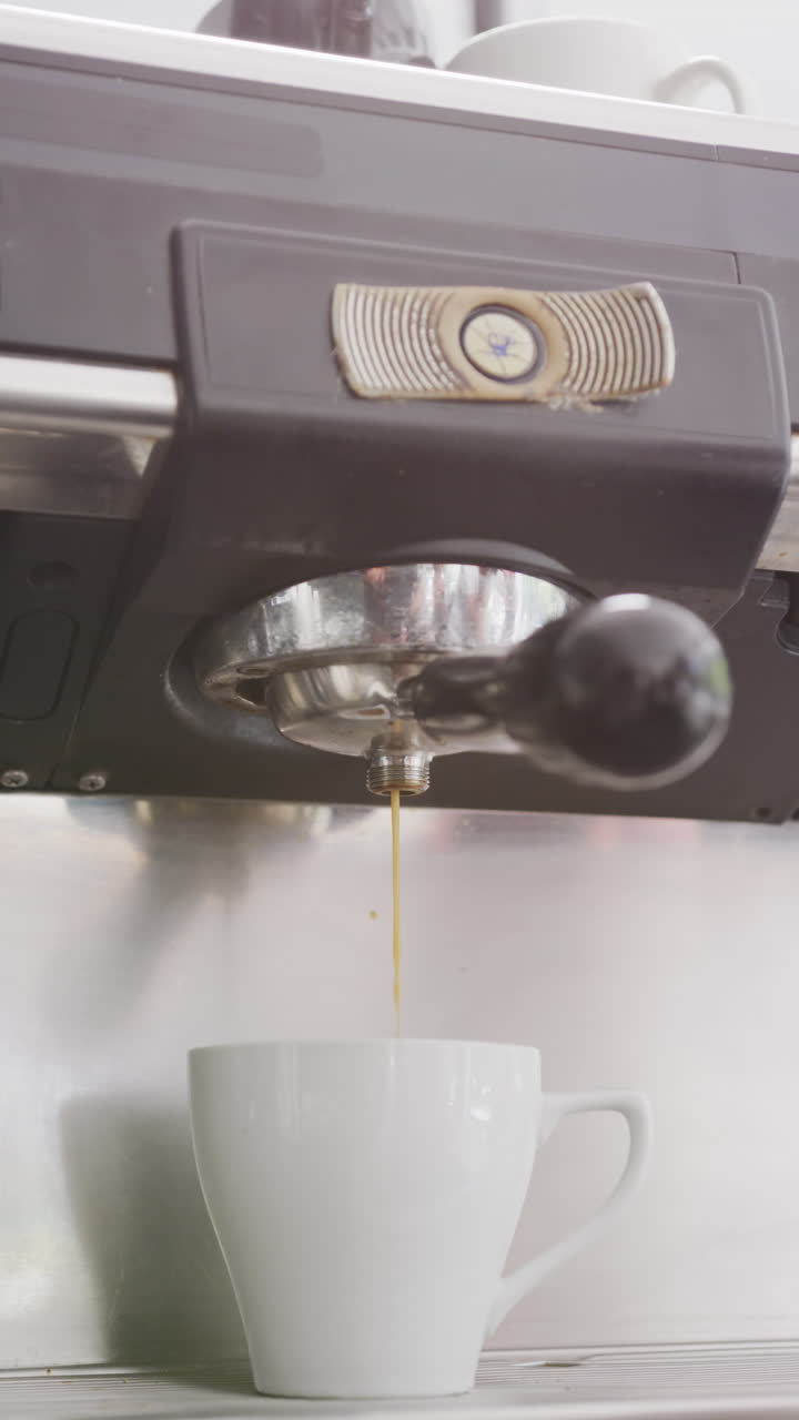 Vertical video of close up of working coffee machine making coffee in cafe