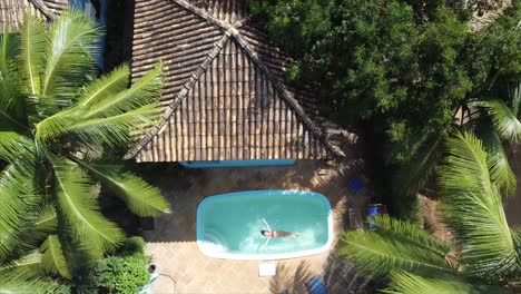 girl floating in swimming pool panning up to brazil's atlantic ocean