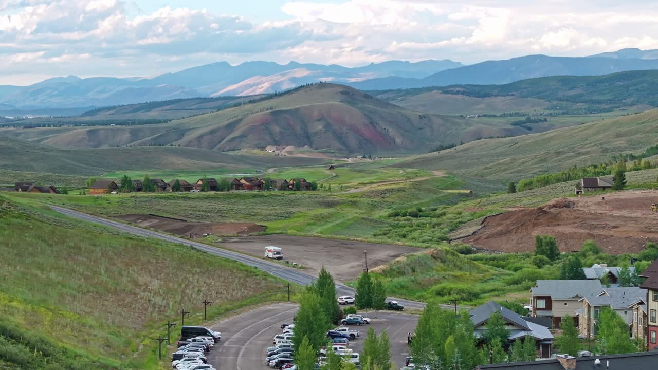 산의 바닥에서 멀리 떨어진 집과 콘도와 함께 스키 리조트 위의 항공 트럭 텔레포토 팬