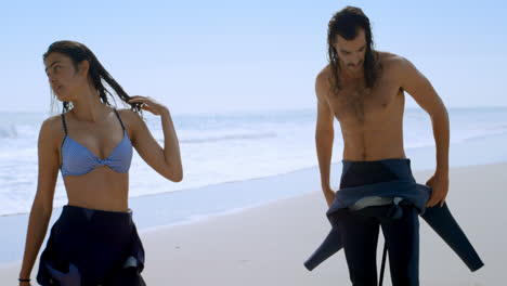 una pareja de surfistas cambiando sus trajes de buceo 4k