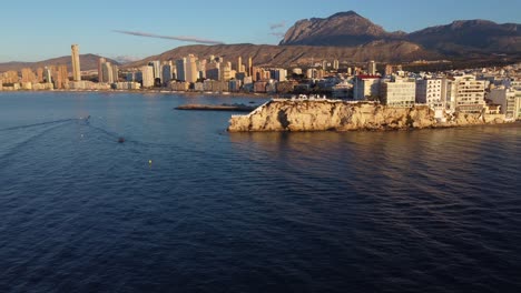 drone flying towards coastline of benidorm in alicante at sunrise time