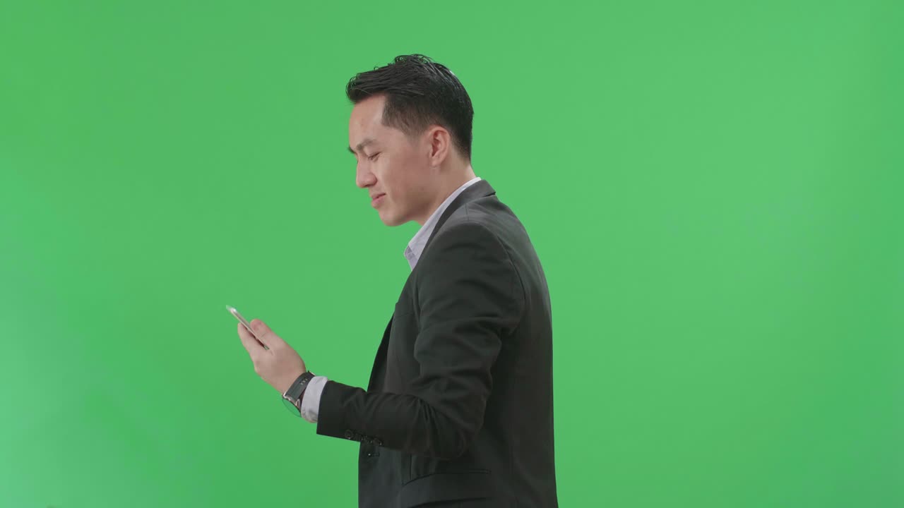 Side View Of Asian Business Man Use Tablet While Walking On Green Screen Chroma Key