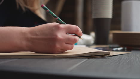 woman writes sitting in courtyard with wooden buildings