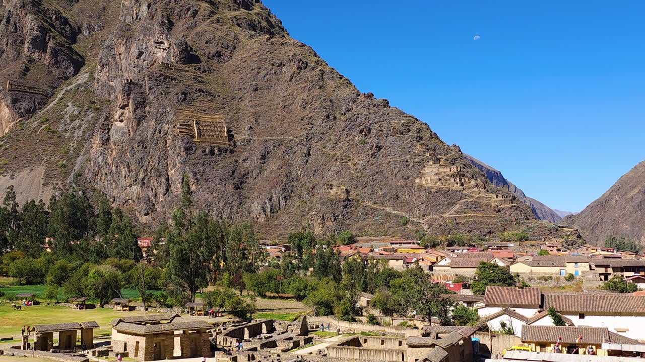 A cinematic view of the ancient Pinkuylluna Inca granaries, or storehouses, carved into the mountainside overlooking the historic town of Ollantaytambo in Peru