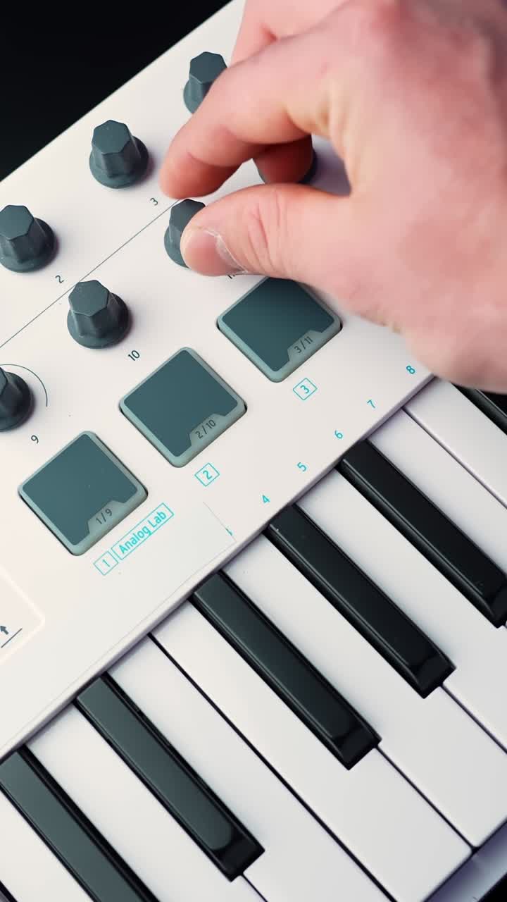 Primo piano verticale di una mano che suona note su una tastiera controller MIDI bianca con profondità di campo ridotta, ideale per la produzione musicale, il songwriting e b-roll da studio.