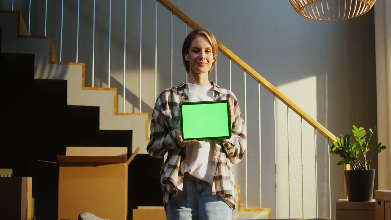 mujer sosteniendo una tableta con pantalla verde en un nuevo hogar