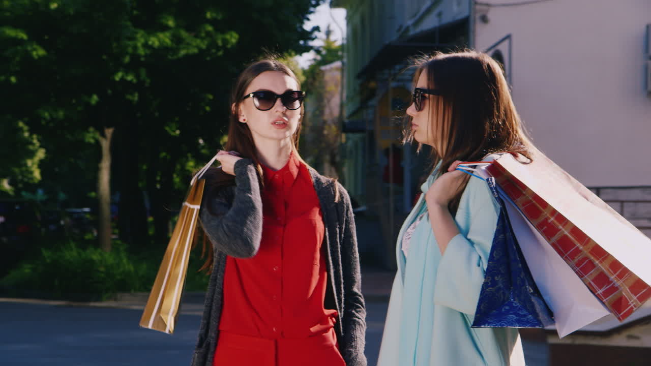 dos mujeres hablan con entusiasmo sobre sus compras en las manos sosteniendo bolsas de compras video hd