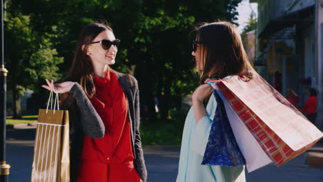 two women enthusiastically talk about their purchases in the hands holding shopping bags hd video