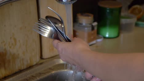 Manos-De-Mujer-De-Primer-Plano-En-Cámara-Lenta-Limpiando-Cubiertos-Con-Agua-Del-Grifo