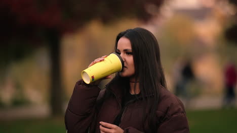 an attractive lady is drinking coffee while on iulius park, cluj-napoca in romania