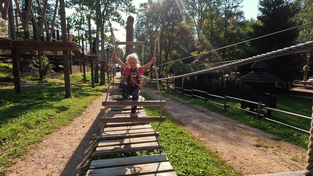 niña feliz jugando en la atracción de tarzán en el patio de recreo en el parque de atracciones