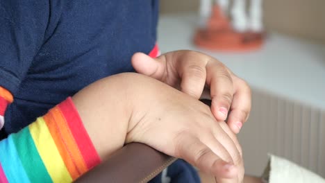 manos de niño y camisa a rayas de arco iris