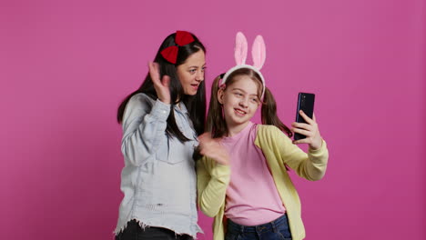 Little-schoolgirl-and-her-mom-talking-on-videocall-meeting-in-studio