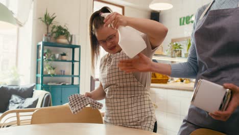 mujer caucásica con síndrome de down limpiando la mesa en el café