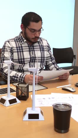 male engineer assembling a miniature wind turbine model at his desk