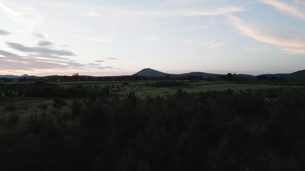 Stort berg bakom en skog vid solnedgång