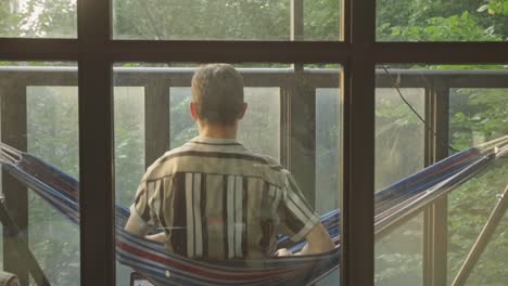 Man-Sit-On-A-Hammock-While-Looking-At-The-View-From-The-Veranda