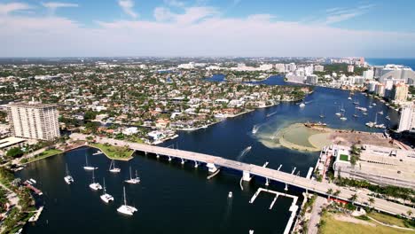 aerial shot of bridge and city beach and sand with calm waters buildings on the side blue water blue sky palm trees ft