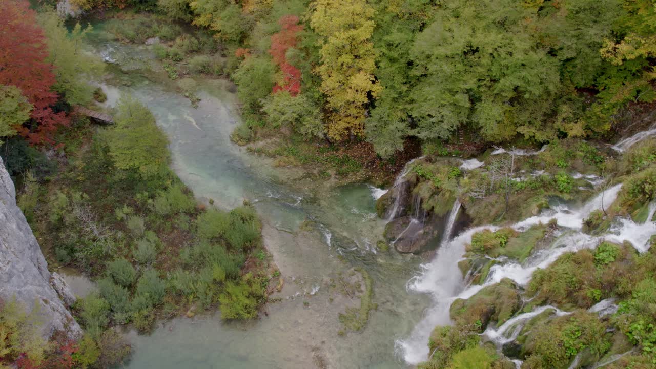 Ripresa con drone di una cascata avvolta nella nebbia e un lago abbracciati da una fitta foresta, Croazia
