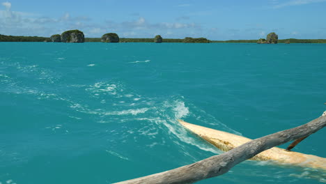 canoa tradicional, o piragua, velas upi bay, rocas flotantes en la distancia