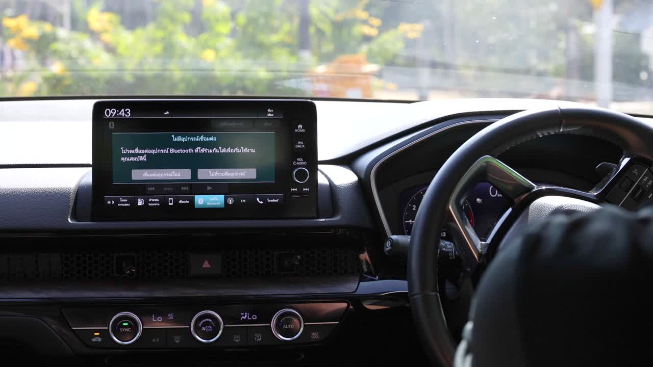 Interior car view showing console and steering wheel in motion, with lush greenery outside, captured in daylight