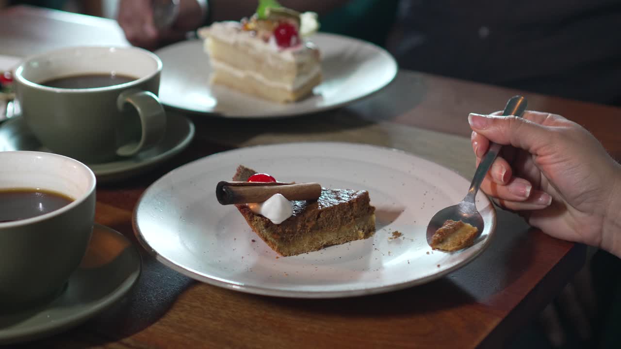 여성은 호박 브라우니 크림 파이 디저트를 즐기고, 여성 손은 파이 디제트를 먹습니다.