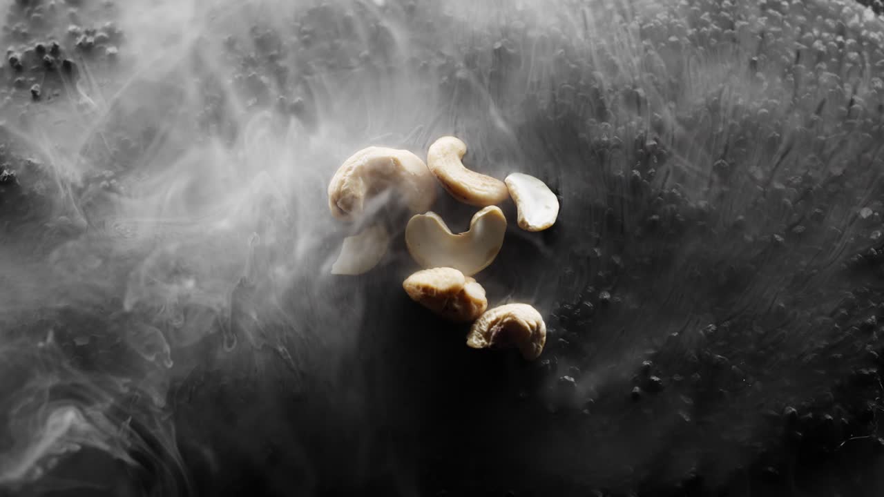 unas cuantas nueces de caju están siendo asadas en un lecho de rocas negras calientes