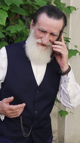 an older man with a white beard on a phone call