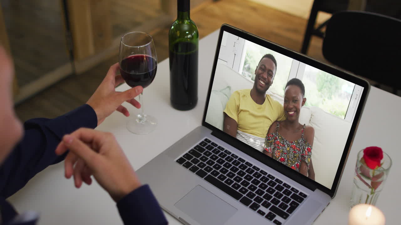 Mid section of african american woman drinking wine while having a video call on laptop at home