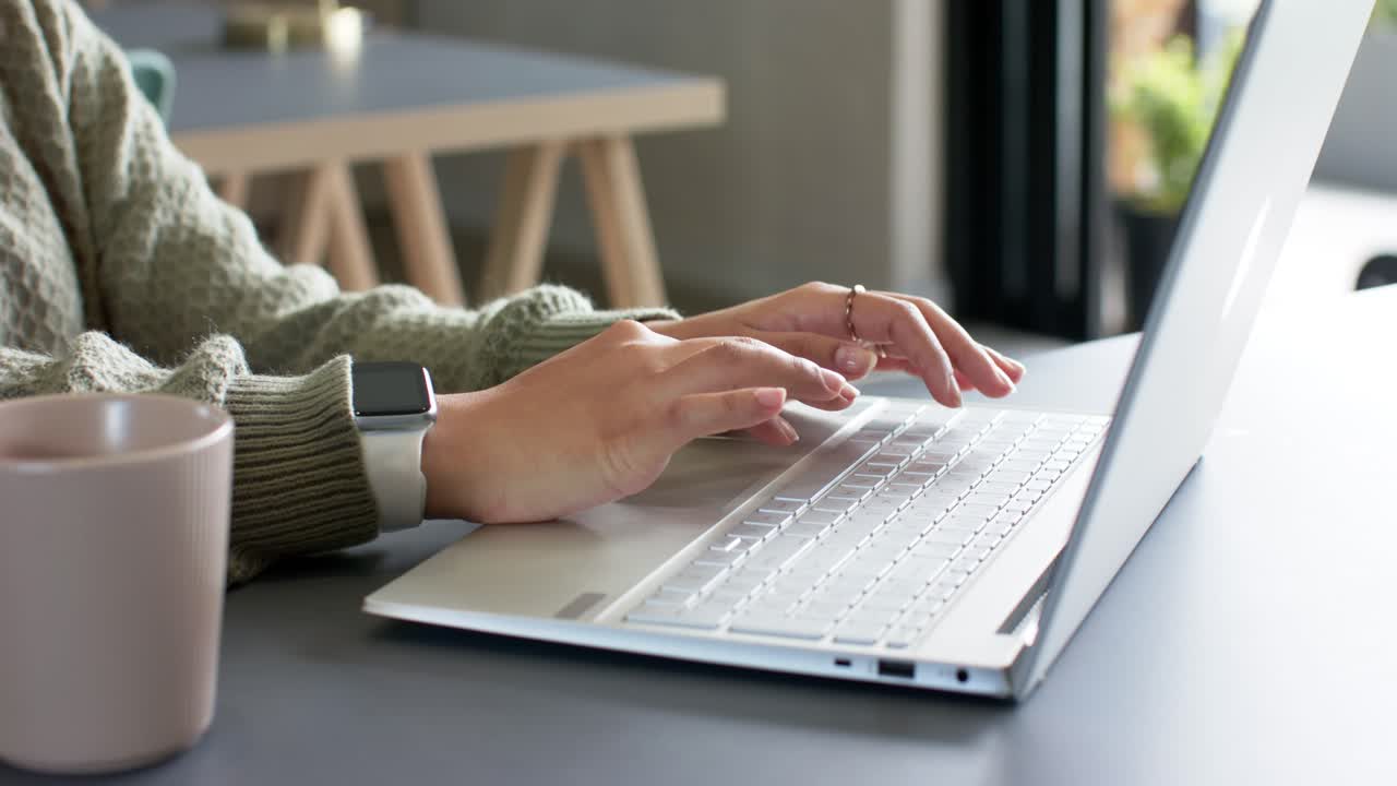 Un dattilografo si sistema alla scrivania accanto al laptop e preme i tasti mentre si sistema il polso durante una sessione remota
