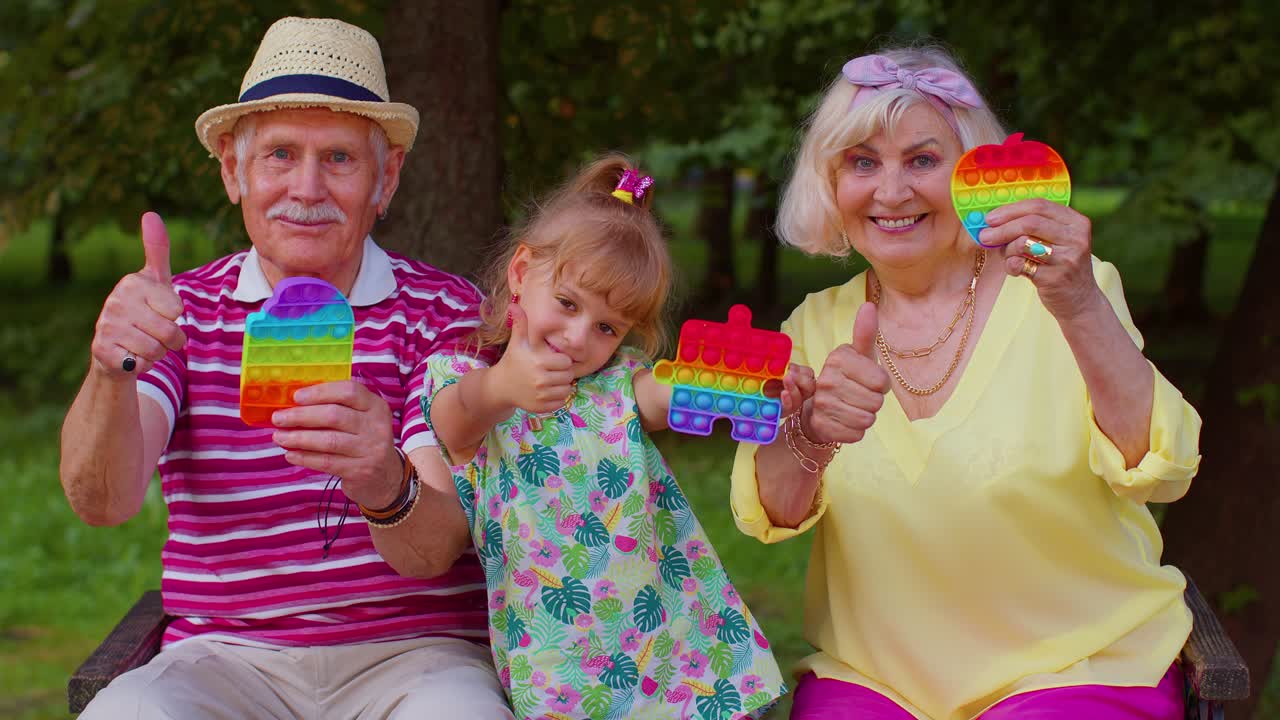 abuela mayor sonriente abuelo con la nieta jugando a apretar juego de juguete anti-estrés