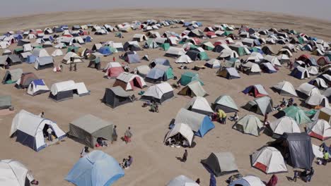 aerial view of a refugee camp with many colorful tents spread across a vast desert landscape, providing temporary shelter for displaced people seeking safety and refuge