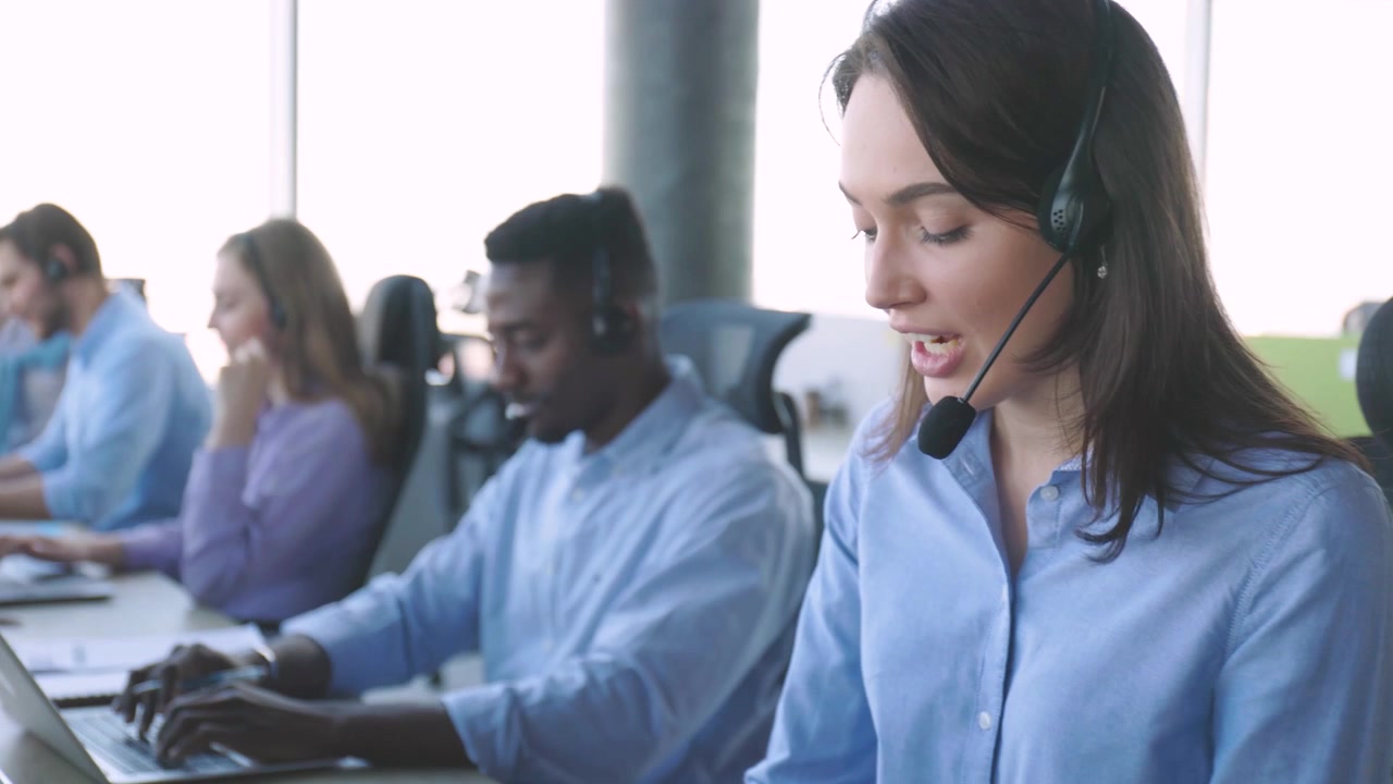 Diverse Call Center Agents Working and Talking on Headsets in Modern Office