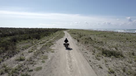 video with drone "follow me" to a motorcyclist driving along the beach